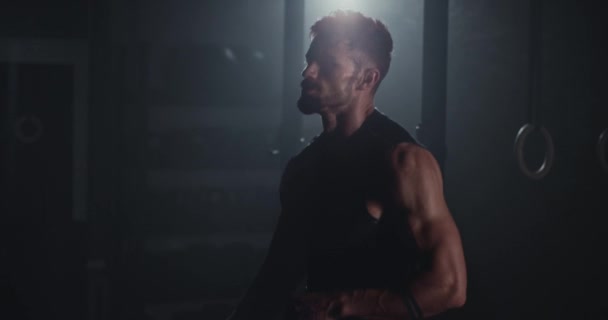 Przed kamerą przystojny facet w ciemnej klasie cross fitness kończy swój intensywny trening — Wideo stockowe