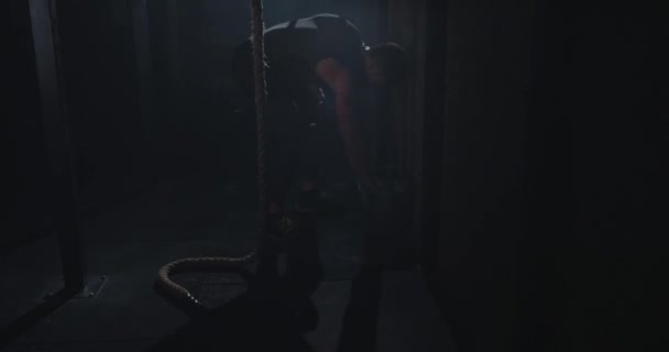 Cross fit anéis cara com um corpo forte começar a fazer o seu treino duro em uma aula de ginástica escura — Vídeo de Stock