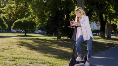 Güneşli bir günde, sokağın ortasında muhteşem görünümlü sarışın bir kadın elektrikli scooterıyla bir yerde durur ve akıllı telefonuyla bir mesaj yazar. ARRI Alexa Mini 'de çekilen