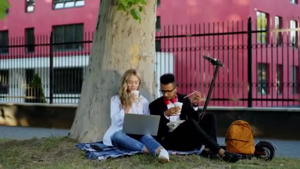 Accanto a un moderno college al momento della pausa due signora prendere il suo computer portatile per fare un po 'di lavoro il suo collega è venuto accanto a lei con un po' di caffè e tablet digitale per trascorrere del tempo insieme — Video Stock