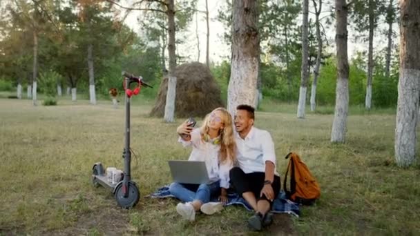 Selfie czas w naturze na trawie wieloetniczna para bardzo podekscytowany podczas chłodzenia czas zrobić kilka zdjęć dla wspomnień cieszyć się razem — Wideo stockowe