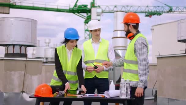 On the top of construction site group of architect and engineer with a pretty lady assistance analyzing the plan of construction they using a modern digital tablet. Shot on ARRI Alexa — Stock Video