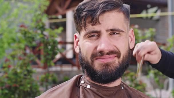 Charismatic man at home in the garden in front of the camera closeup finish his haircut off barber man take the big brush to clean the hair off the face and neck — Stock Video