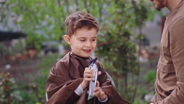 Привлекательный 5-летний мальчик готовится к стрижке парикмахер дает мальчику электронный клипер, прежде чем он начнет работать в середине сада. Снимок на ARRI Alexa Mini — стоковое видео