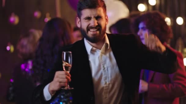 Sonriendo gran chico carismático en la fiesta de cosas disfrutando de la noche bailando con una copa de champán y mirando directamente a la cámara. 4k — Vídeo de stock