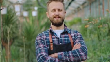 Fotoğraf makinesinin bahçıvanına yakın şık bir üniformayla el ele tutuşup büyük bir çiçek serasında doğrudan kameraya bakıyor.