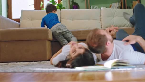 Familie dag samen thuis in de woonkamer gelukkige ouders liggen op de vloer charismatische kleine jongen kwam naar de ouders en chatten — Stockvideo