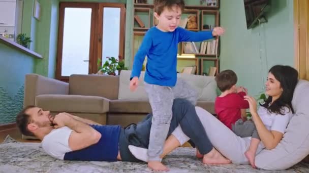Ciesząc się razem czas młoda rodzina mają chłodny dzień w domu na podłodze robią sport rozmawiając razem korzystając z czasu — Wideo stockowe