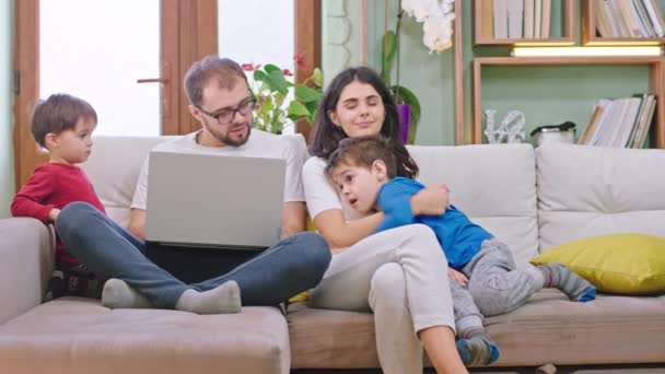 Pandemia 2019 giovane famiglia stare a casa in quarantena davanti alla telecamera passano del tempo insieme papà a lavorare sul suo portatile madre giocare con i bambini — Video Stock