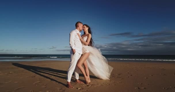 Karizmatik erkek ve kadın birbirlerine sarılıyorlar ve kumsal kenarında birlikte anın tadını çıkarıyorlar. — Stok video