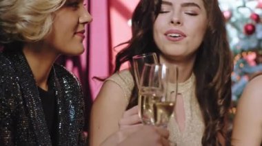 Noel partisinde harika güzel bir bayanın portresi. Kanepede oturup aynı anda hem sosyalleşip hem de şampanya içiyorlar.