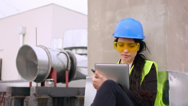 Piękna kobieta w kasku bezpieczeństwa przed kamerą na szczycie placu budowy weź cyfrowy tablet, aby zrobić notatki jest młodym inżynierem trzymającym cyfrowy tablet — Wideo stockowe