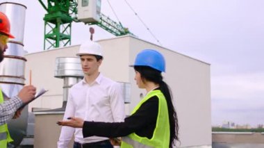 İnşaat planlarını analiz eden uzmanlar grubunun tepesinde güvenlik ekipmanlarını kullanarak inşaat ve dijital tablet planlarını kullanıyorlar.