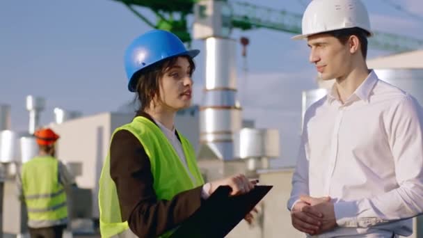 魅力的な女性エンジニアと良い探してビジネスマンは、次の建設の計画について建設現場の上で議論しています彼らは握手の終わりに良い会話を持っています — ストック動画