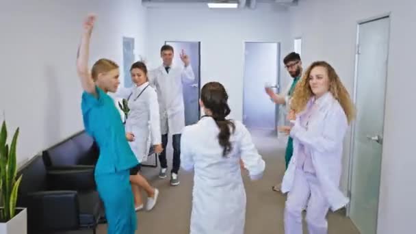 Médicos e enfermeiras entusiasmados com um grande sorriso dançando na frente da câmera em um corredor do hospital eles se sentem muito felizes — Vídeo de Stock