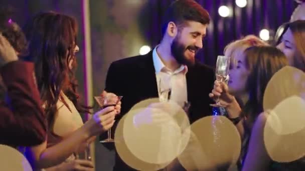 Grupo de jóvenes guapos en la fiesta que sonríen grandes disfrutando de la fiesta bebiendo un poco de champán y bailando — Vídeo de stock