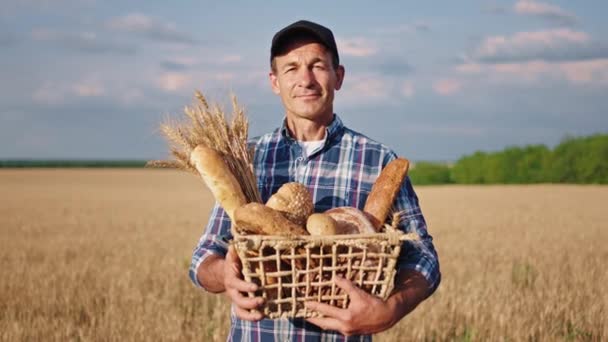 Portré egy idős gazdáról, aki boldog és mosolygós, kezében egy doboz friss kenyérrel, és egyenesen a kamerába néz. — Stock videók