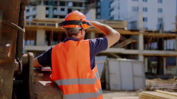 İnşaat alanındaki olgun inşaat işçisi. İnşaattaki güvenlik kaskını taktığı binaya bir bak. — Stok video