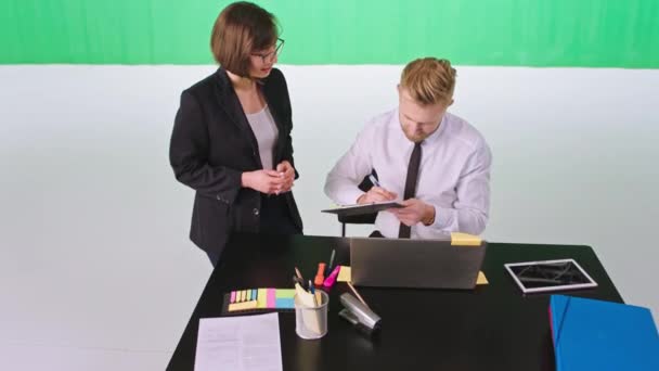 Zielony tło studio piękny asystent i jej menedżer Dyskusja ona wziąć niektóre zadania do zrobienia — Wideo stockowe