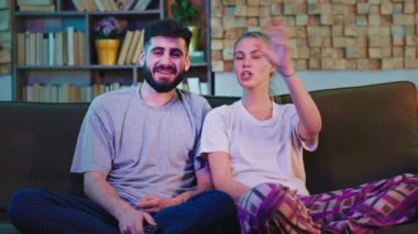 Oturma odasındaki kanepede oturan genç çift kameranın önünde televizyon seyrediyor, tartışıyorlar ve birlikte gülümsüyorlar. ARRI Alexa Mini 'de çekilen