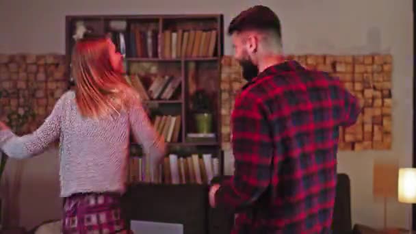 Snygg dam och kille ha kul tillsammans hemma i pyjamas dans glada tillsammans i vardagsrummet — Stockvideo