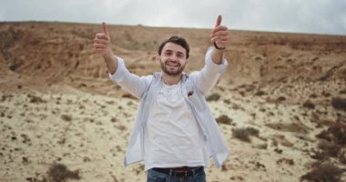 Kameraya doğru bakan çekici bir adam büyük bir benzerlik gösteriyor ve doğanın ortasında çok heyecanlı hissediyor.