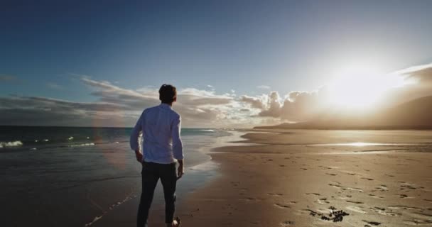 O zachodzie słońca budzący się facet na plaży nad morzem ma czas na medytację sam na sam. — Wideo stockowe