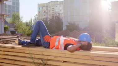 İnşaat işçisi Afro-Amerikan 'da molada ormanda kestirirken uyanır, kaskını alır ve işe gider.