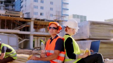 Molada dizüstü bilgisayarı olan güzel bir mühendis hanım orta yaşlı ustabaşıyla görüşüyor. Öğlen vakti güvenlik kaskı ve gözlük takıp bir şeyleri analiz ediyorlar.