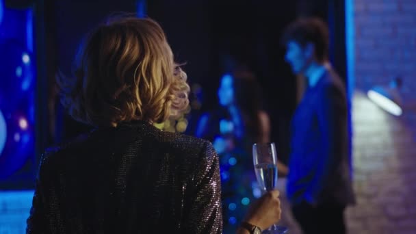 Na imprezie blondynka z krótkimi włosami zbliżyła się do swoich przyjaciół i zacząć rozmawiać i cieszyć się nocną atmosferą party — Wideo stockowe