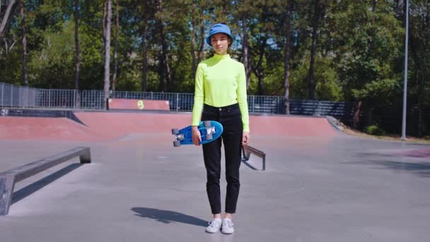 Hezká asijská dáma v moderním skate parku drží skateboard a dívá se přímo do kamery má hipster styl. Shot na ARRI Alexa Mini — Stock video