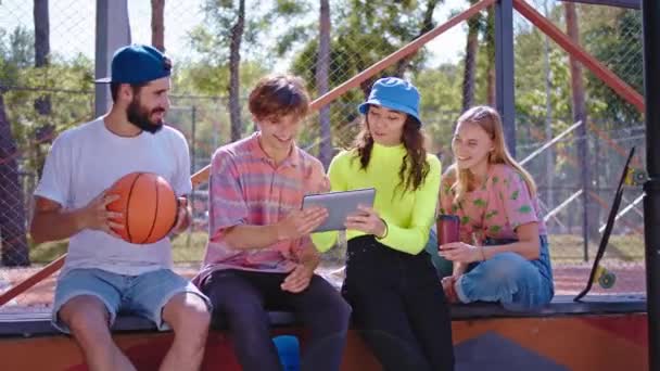 Moderno grupo de parque de amigos multiétnicos atractivos disfrutando del tiempo juntos viendo una película divertida en la tableta electrónica que discuten juntos — Vídeos de Stock