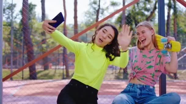 多民族的两位女士朋友带着大大的笑容，用现代智能手机在镜头前摆出一副照片，为回忆做了些自拍照 — 图库视频影像