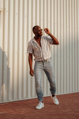 Genç moda giymiş gömleğini giyip sokakta yürüyor