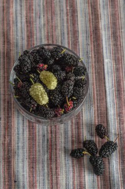 Siyah arka plan üzerinde masaüzerinde bir cam kase dut