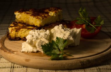Gece çerez, ulusal Balkan pasta Banitsa, domates, otlar ve peynir masada ahşap bir tahta üzerinde.