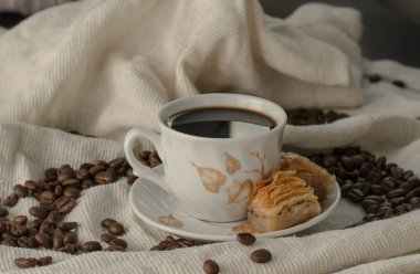 Kahve ve baklava masada, tahıllı bir masa örtüsünün üzerinde.