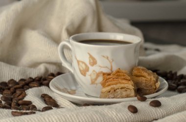 Kahve ve baklava masada, tahıllı bir masa örtüsünün üzerinde.