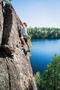 göl üzerinde yüksek bir kayanın üzerinde bir dağcı