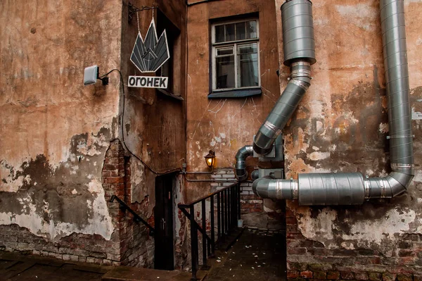 在圣彼得堡市中心的房子的肮脏的墙壁上的金属管 — 图库照片