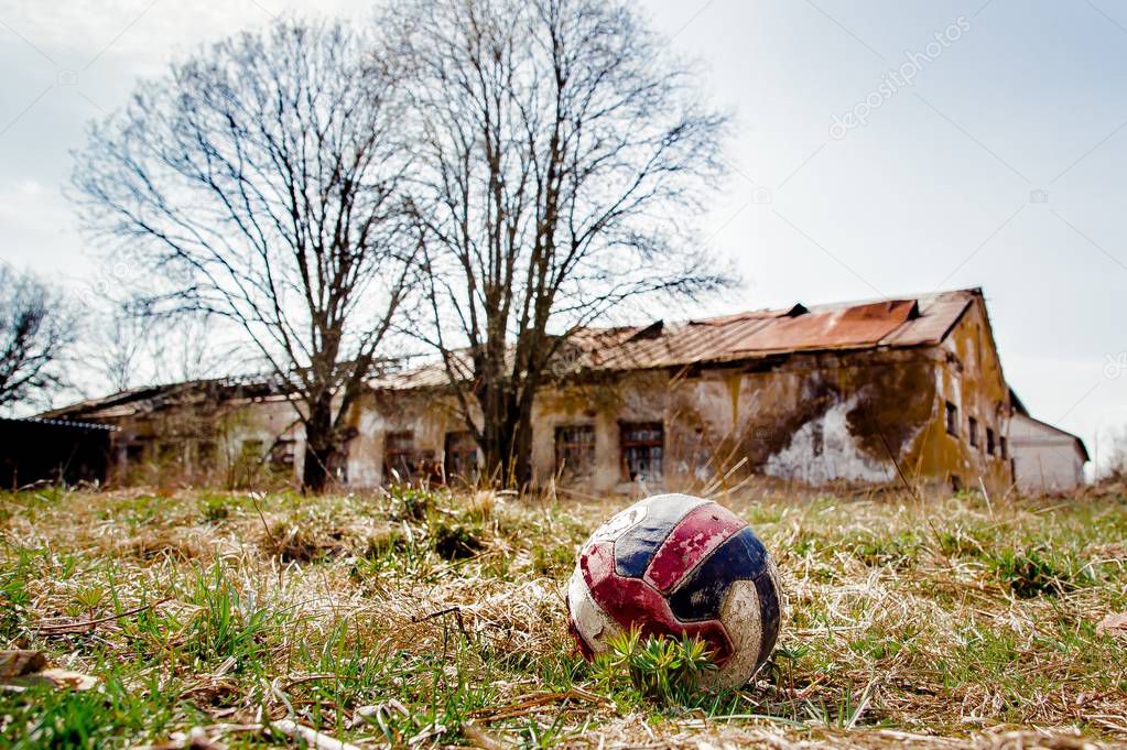 battered ball with abandoned building on the background