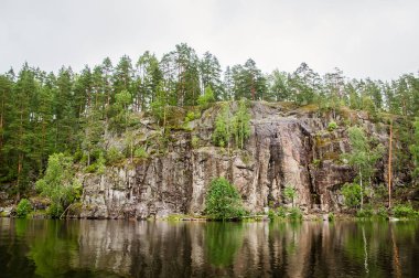 kıyıda kaya ve orman yansıması ile sakin göl