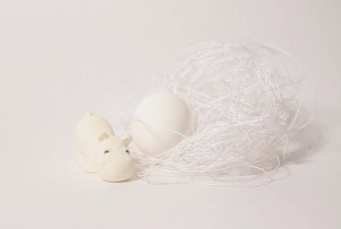 Beyaz arka planda yuvası ve yumurtası olan beyaz oyuncak su aygırı.