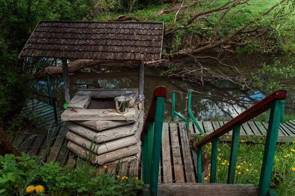 Old rustic wooden well on the river with wooden staircase with railing — Stock Image Old Rustic Wooden Well River Wooden Staircase Railing Stock Picture