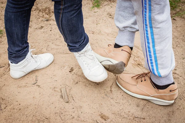A girl and a guy greet each other with their feet. After the quarantine, people come up with a new way to say Hello