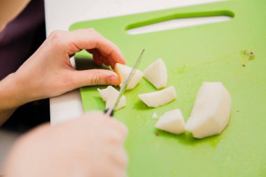 Çocukların elleri elmaları parçalara ayırdı. Çocuk meyve salatası hazırlıyor.