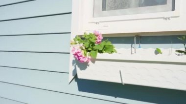 Pencerenin altında çiçekler olan asılı bir çiçek sepeti. Provence tarzında ev dekoru