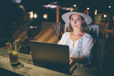 Tropikal plaj bar kafede dizüstü bilgisayar kullanan genç ve güzel kadın.