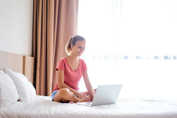 Ganska Ung Kvinna Använder Laptop Medan Sitter Sängen — Stockfoto