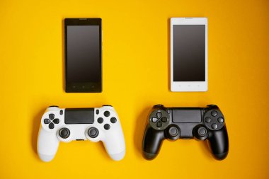 Bilgisayar oyun rekabet. Oyun kavramı. Beyaz ve siyah akıllı telefonlar ve sarı zemin üzerine oyun çubukları.
